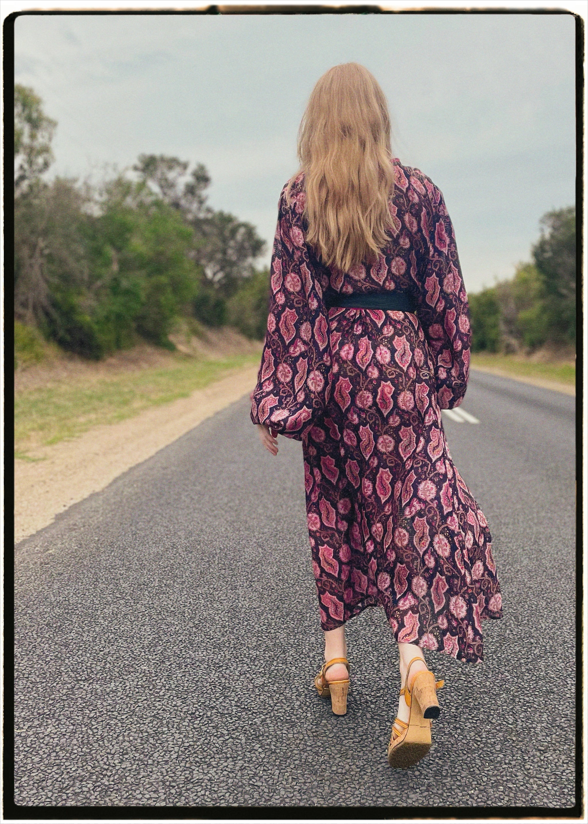 Woman wearing a bohemian style balloon sleeved wrap dress made from vintage repurposed Indian silk crepe sari in front of a plain 