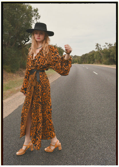 Woman wearing a bohemian style balloon sleeved wrap dress made from vintage repurposed Indian silk crepe sari in front of a plain 