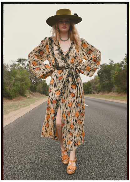 Woman wearing a bohemian style balloon sleeved wrap dress made from vintage repurposed Indian silk crepe sari in front of a plain 