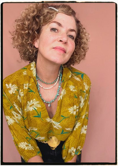 Woman wearing a bohemian style balloon sleeved blouse made from vintage repurposed Indian silk crepe sari in front of a plain background