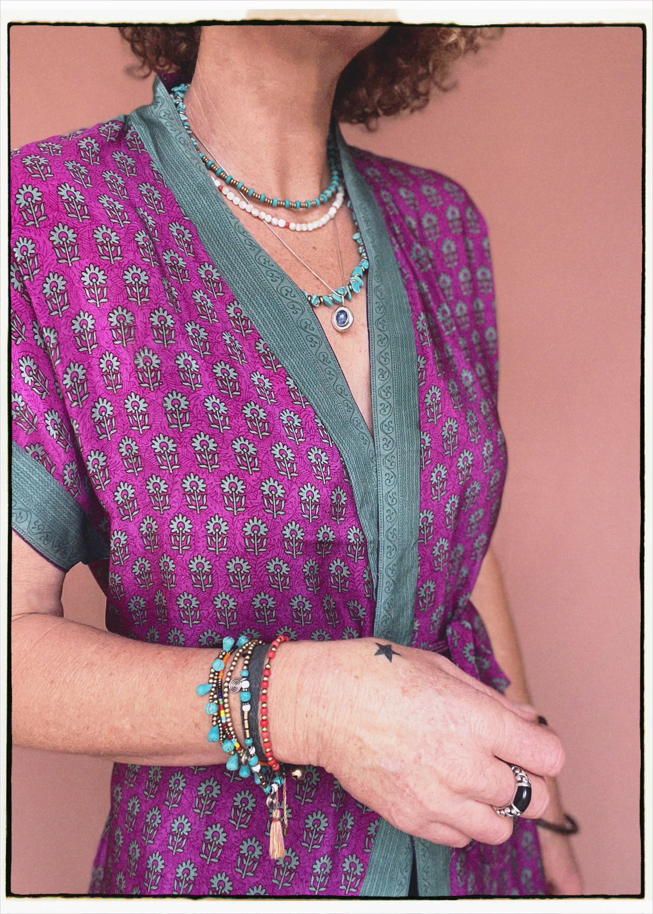 Woman wearing a bohemian style balloon sleeved patterned blouse made from vintage repurposed Indian silk crepe sari in front of a plain background