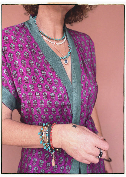 Woman wearing a bohemian style balloon sleeved patterned blouse made from vintage repurposed Indian silk crepe sari in front of a plain background